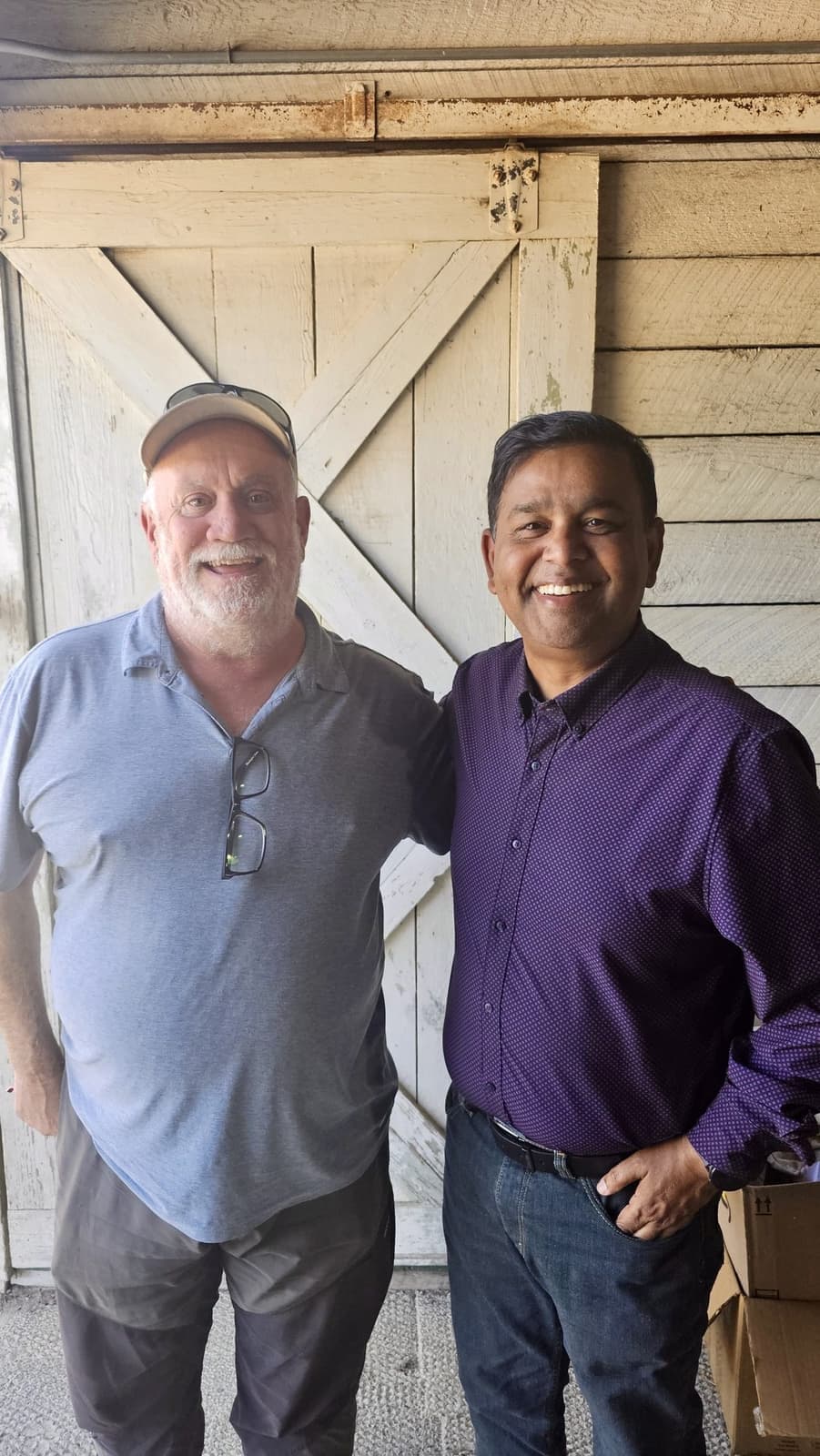 David Schimel and Ravi Sinha standing side by side in front of a weathered barn door at the Dangermond Preserve.