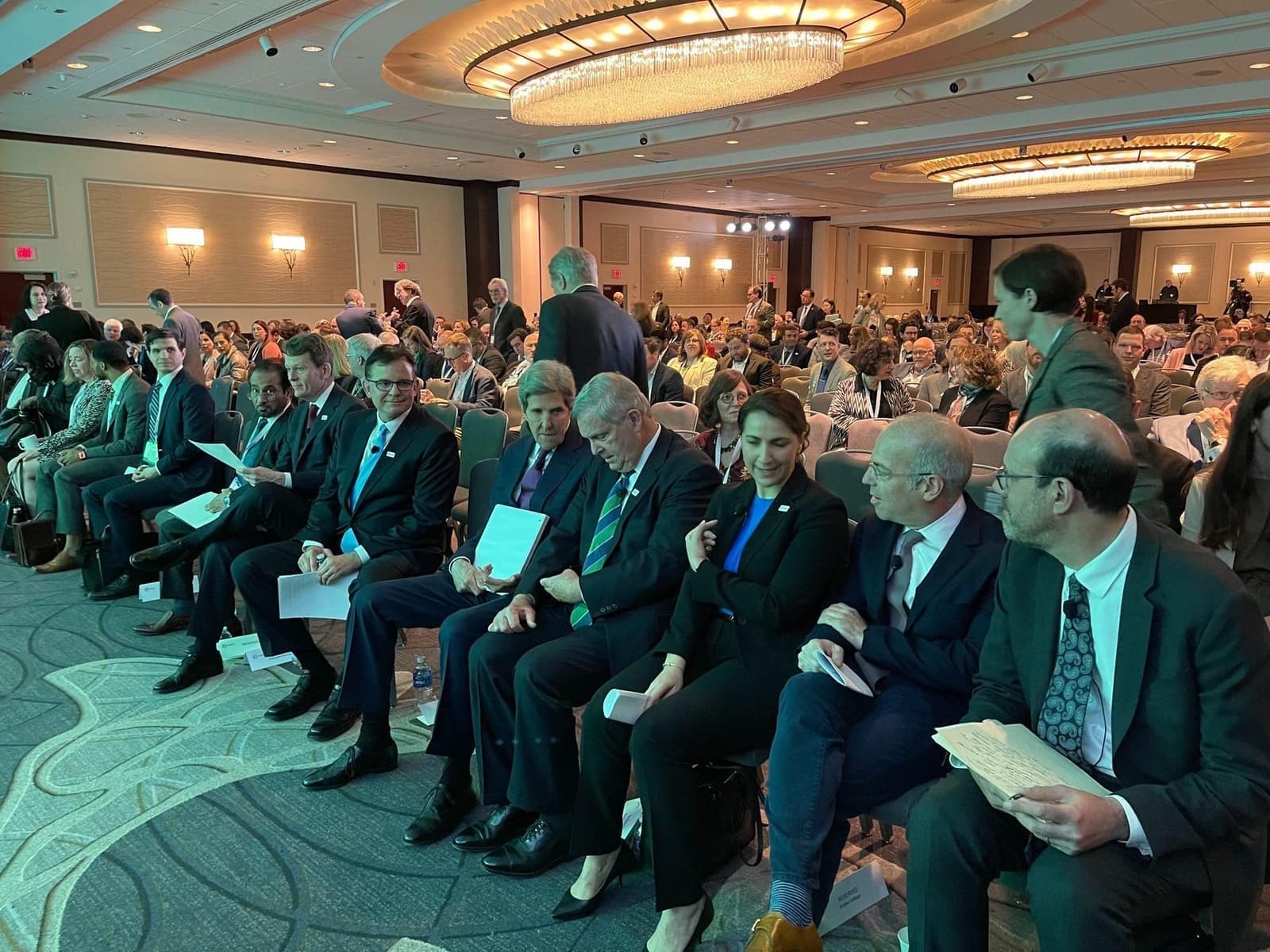 A packed conference hall of seated delegates waiting for a climate summit session to begin.