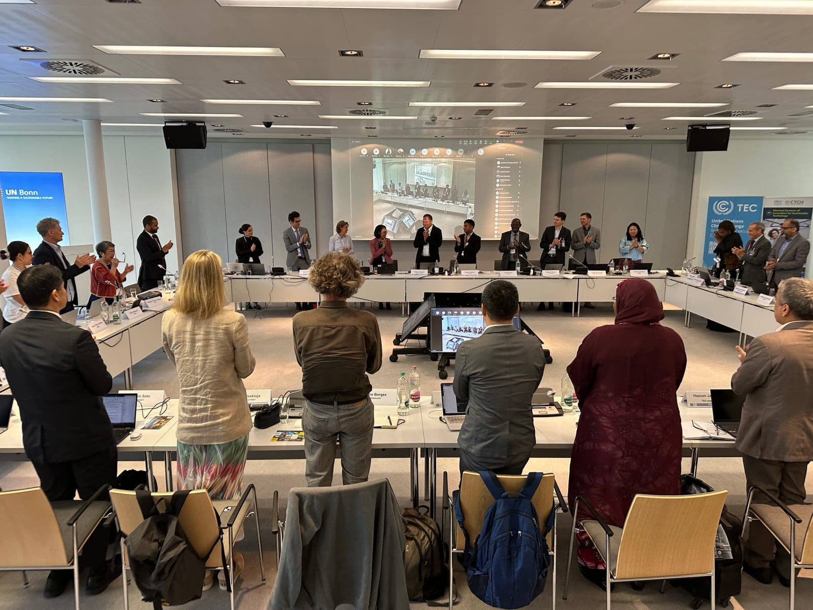 Delegates standing and applauding around a U-shaped table at the UNFCCC TEC and CTCN joint meeting in UN Bonn.